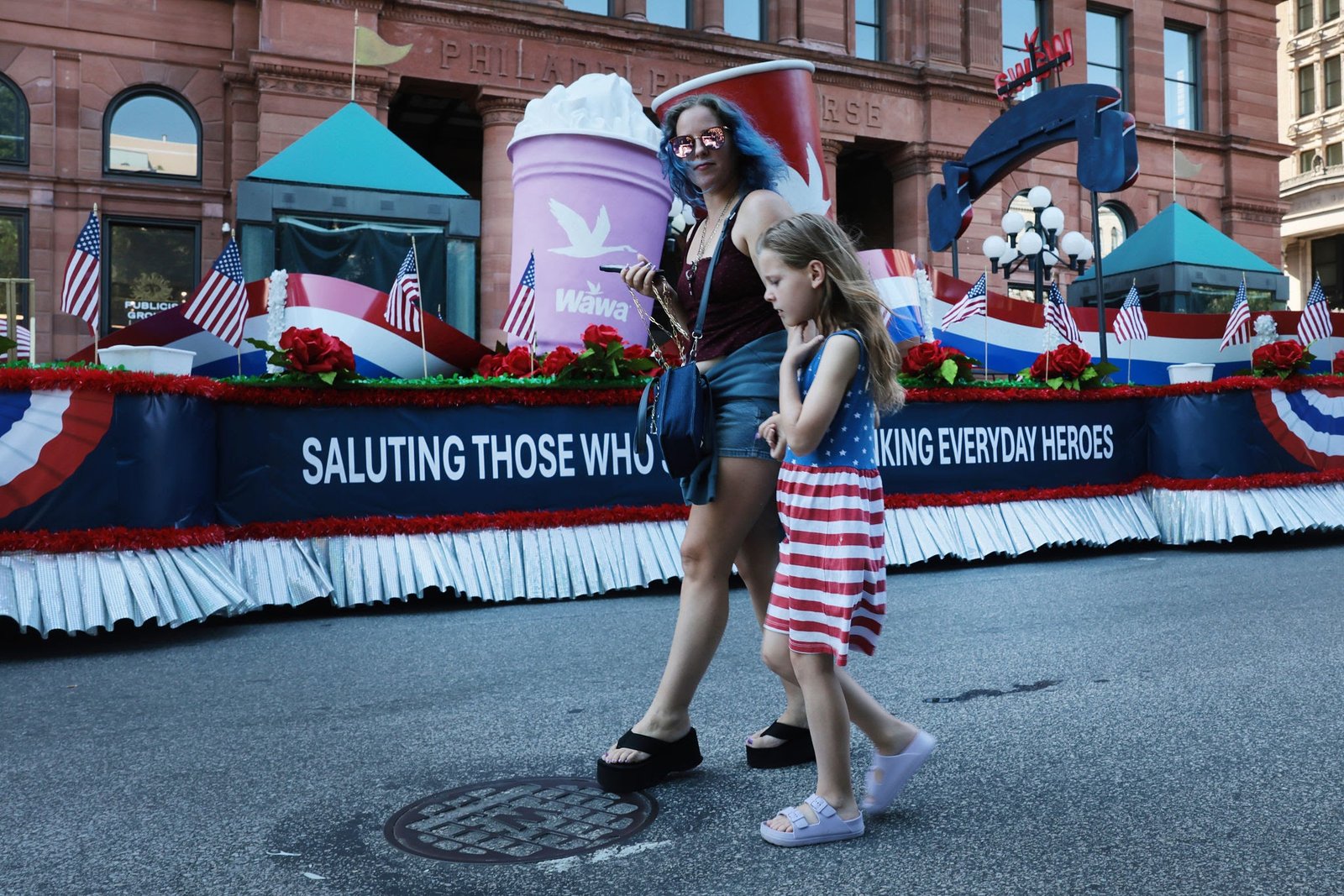 People walking past an Independence Day parade float during extreme heat